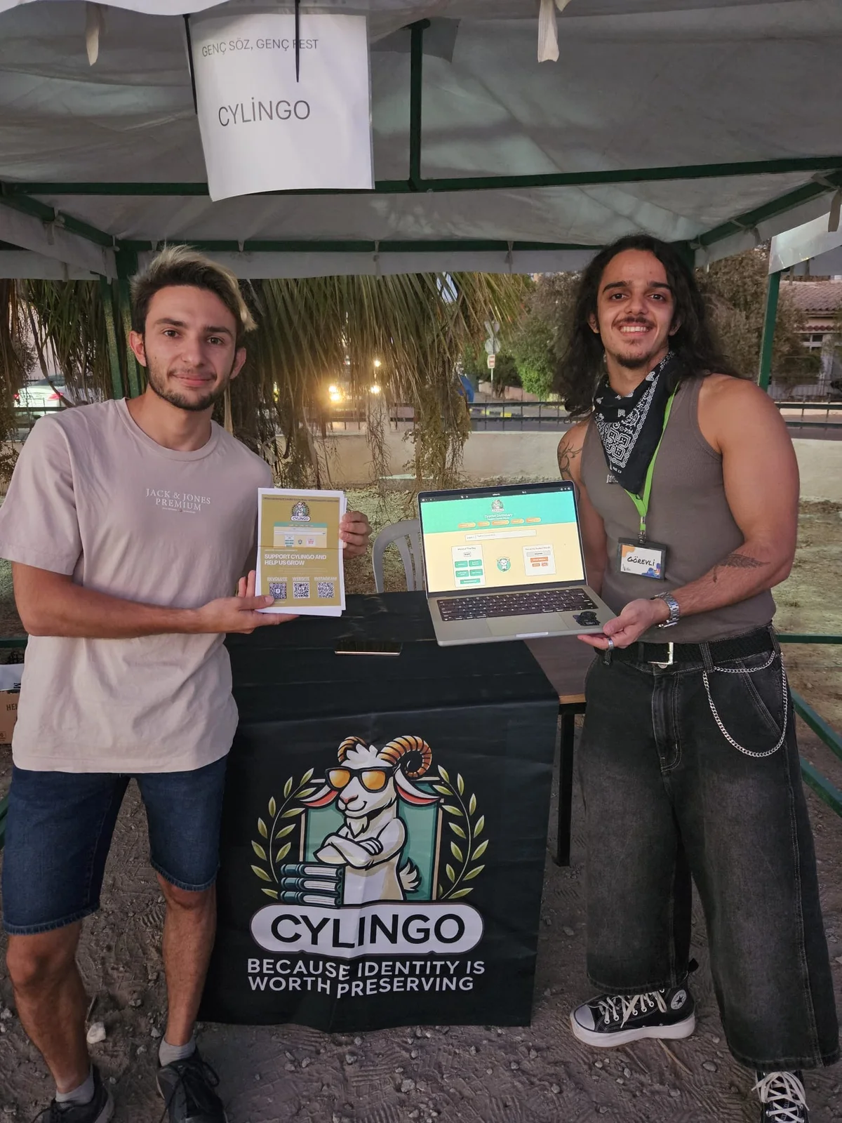 Cylingo representatives at their festival table with a laptop, leaflets and Cylingo banner